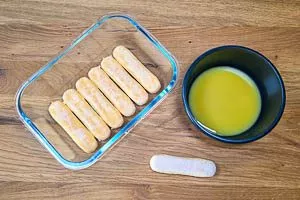 Löffelbiskuits in den Orangensaft tauchen und in die Form geben