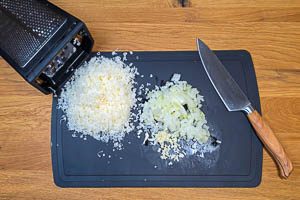 Zwiebel und Knoblauch vorbereiten und Parmesan fein reiben.