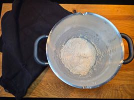 Teig in der Schüssel mit den Händen heben und falten