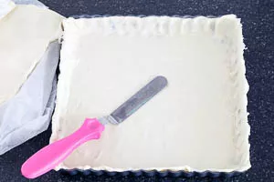 Quiche-Form mit Butter einfetten und Blätterteig auslegen.