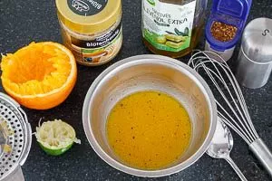 Dressing aus Orange, Zitrone, Honig, Olivenöl, Chiliflocken und Salz anrühren.