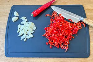 Knoblauch und Peperoni in Scheiben und Ringe schneiden.