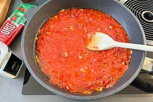 Tomatenmark und stückige Tomaten dazugeben und würzen.