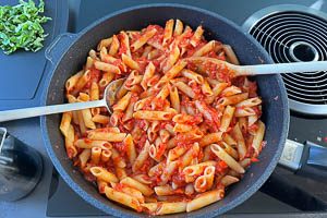 Penne mit etwas Nudelwasser zu der Soße geben und gut verrühren. Anschließend gut ziehen lassen und servieren.