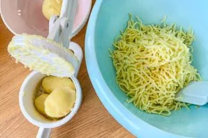 Gekochte Kartoffeln pressen und in eine Schüssel geben.