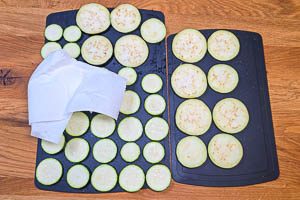 Zucchini und Aubergine mit Küchenpapier abtupfen.