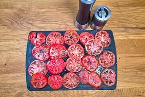 Strauchtomaten horizontal in etwa 1 cm dicke Scheiben schneiden. Anschließend mit Salz und Pfeffer würzen.