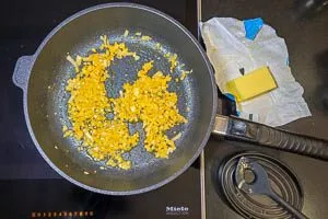 Zwiebeln und Knoblauch in der selben Pfanne in Butter anbraten.