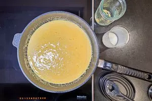 Sahne und Hühnerbrühe zu den Zwiebeln und dem Knoblauch geben. Hitze runter drehen und den Parmesan hinzugeben.