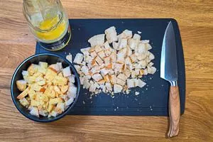 Ein Brötchen in Würfel schneiden und mit Orangensaft vermischen. Das zweite in Würfel für Croutons schneiden.