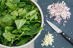 Weitere Zutaten für gefüllte Champignons vorbereiten: Spinat, Zwiebeln und Knoblauch.