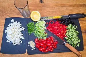 Gemüse für den Salat fein würfeln, Zitronenschale abreiben und Saft auspressen.