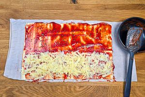 Tomatensoße auf den Teigbahnen verstreichen
