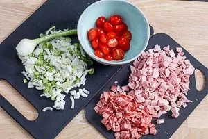 Kirschtomaten, Frühlingszwiebeln, Kochschinken und Salami schneiden
