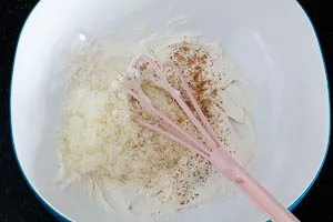 Geriebenen Hartkäse und Muskatnuss in den Ricotta rühren