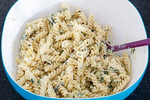 Zucchini-Creme mit den Fusilli-Nudeln vermengen