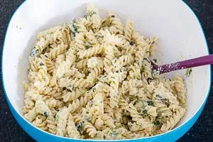 Zucchini-Creme mit den Fusilli-Nudeln vermengen
