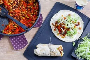 Erwärme die Tortillas und verteile deine Füllung aus Gemüse und Fleisch mit etwas Crème Fraîche darauf.