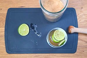 Zucker und Limettenscheiben zerstoßen.