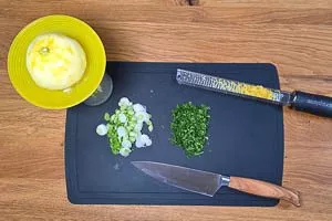 Frühlingsringe klein schneiden, Petersilie waschen und fein hacken und Zitrone auspressen und Zeste abreiben.