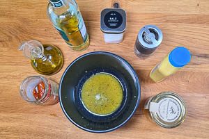 Rühre das Dressing aus dem Öl der Tomaten, Olivenöl, weißem Balsamico-Essig, Salz, Senf, Honig und schwarzem Pfeffer an.