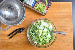 Knoblauch, Erbsen, Frühlingszwiebeln und Reis in einer Schüssel vermengen
