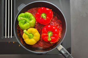 Gefüllte Paprikaschoten in die Soße in einer ofenfesten Pfanne stellen und im Backofen garen