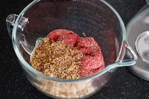 Rinderhackfleisch mit Salz und Pfeffer zu den Semmelbröseln geben