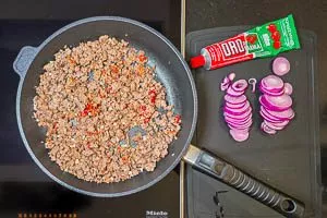 Tomatenmark zur Hackfleisch-Pfanne hinzugeben