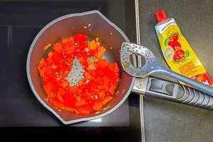 Knoblauch und Tomatenmark in den Topf geben