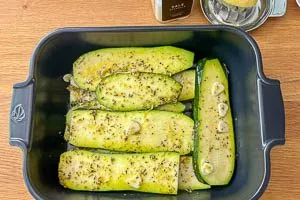 Zucchinischeiben in einer Auflaufform mit der Marinade vermengen