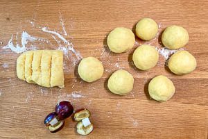 Den Kartoffelteig um die Zwetschgen wickeln.
