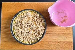 Streusel auf der Pudding-Masse in der Springform verteilen und Kuchen für eine Stunde backen