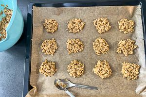 Haferkeksmasse mit einem Teelöffel auf einem Backblech mit Backpapier verteilen