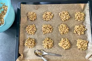 Haferkeksmasse mit einem Teelöffel auf einem Backblech mit Backpapier verteilen