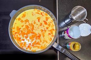 Gemüsebrühe, Kokosmilch und Currypaste zu dem angebratenen Gemüse geben