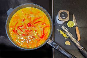 Paprika schneiden und dazugeben. Geriebenen Ingwer dazugeben und das Kürbis-Curry köcheln lassen