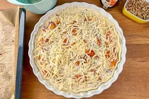 Gemüse, Guss und Käse auf dem Teig verteilen.