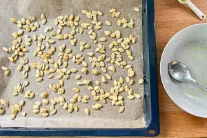 Kürbiskerne auf einem Backblech verteilen und im Ofen rösten