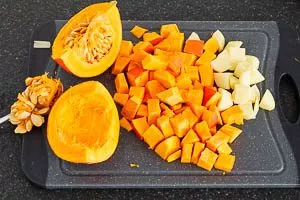 Kürbis waschen, Kerne entfernen und würfeln. Kartoffeln schneiden