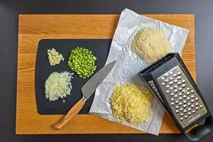 Zwiebeln, Knoblauch und Sellerie waschen und kleinschneiden sowie Käse reiben