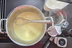 Mehl, Sahne, Gemüsebrühe, Muskat, Salz und Pfeffer einrühren