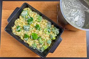 Soße über die Nudeln und den Brokkoli in der Auflaufform geben