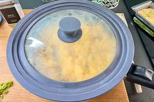 Pfanne vom Herd nehmen und für eine Minute den Deckel drauf geben