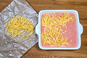 Geriebenen Käse auf dem Auflauf verteilen