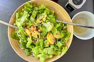 Endivie mit dem Dressing zur Mischung aus Kartoffeln, Apfel, Zwiebel und Speck geben