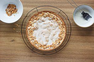 Zuckerguss auf dem Kuchen verteilen und Mandeln darauf verteilen.