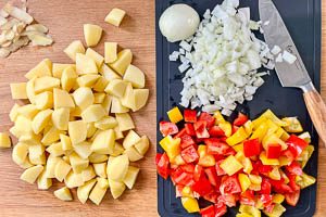 Kartoffeln schälen und schneiden. Zwiebeln und Paprika schneiden.