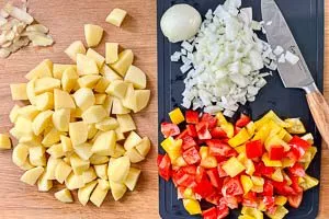 Kartoffeln schälen und schneiden. Zwiebeln und Paprika schneiden.