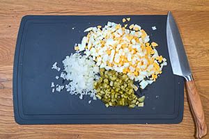 Cornichons, Zwiebeln und gekochte Eier würfeln
